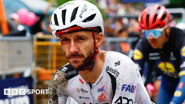 Adam Yates in a torn cycling kit and helmet, both predominantly white