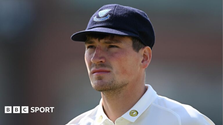 Henry Crocombe looks on, while wearing a blue cap