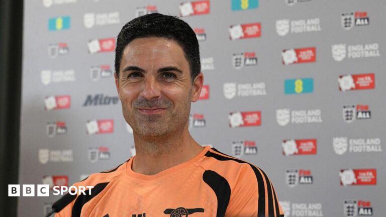 Mikel Arteta stifles a laugh while sitting at a press conference