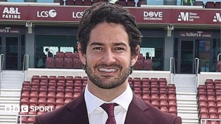 Consortium including Alexandre Pato completes Northampton Town takeover Alexandre Pato standing by side of Sixfields pitch, wearing maroon suit, white shirt, red tie and cream shoes, smiling with hands in pockets.
