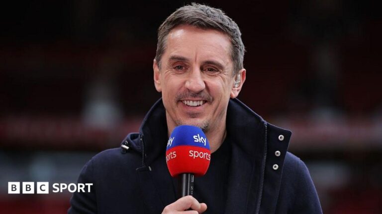 Gary Neville smiling and holding a Sky Sports microphone