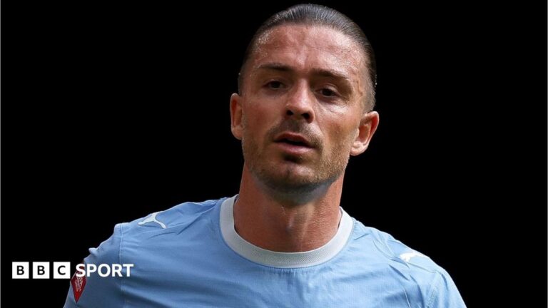 Jack Grealish, wearing Manchester City's sky blue kit, looks on during a match